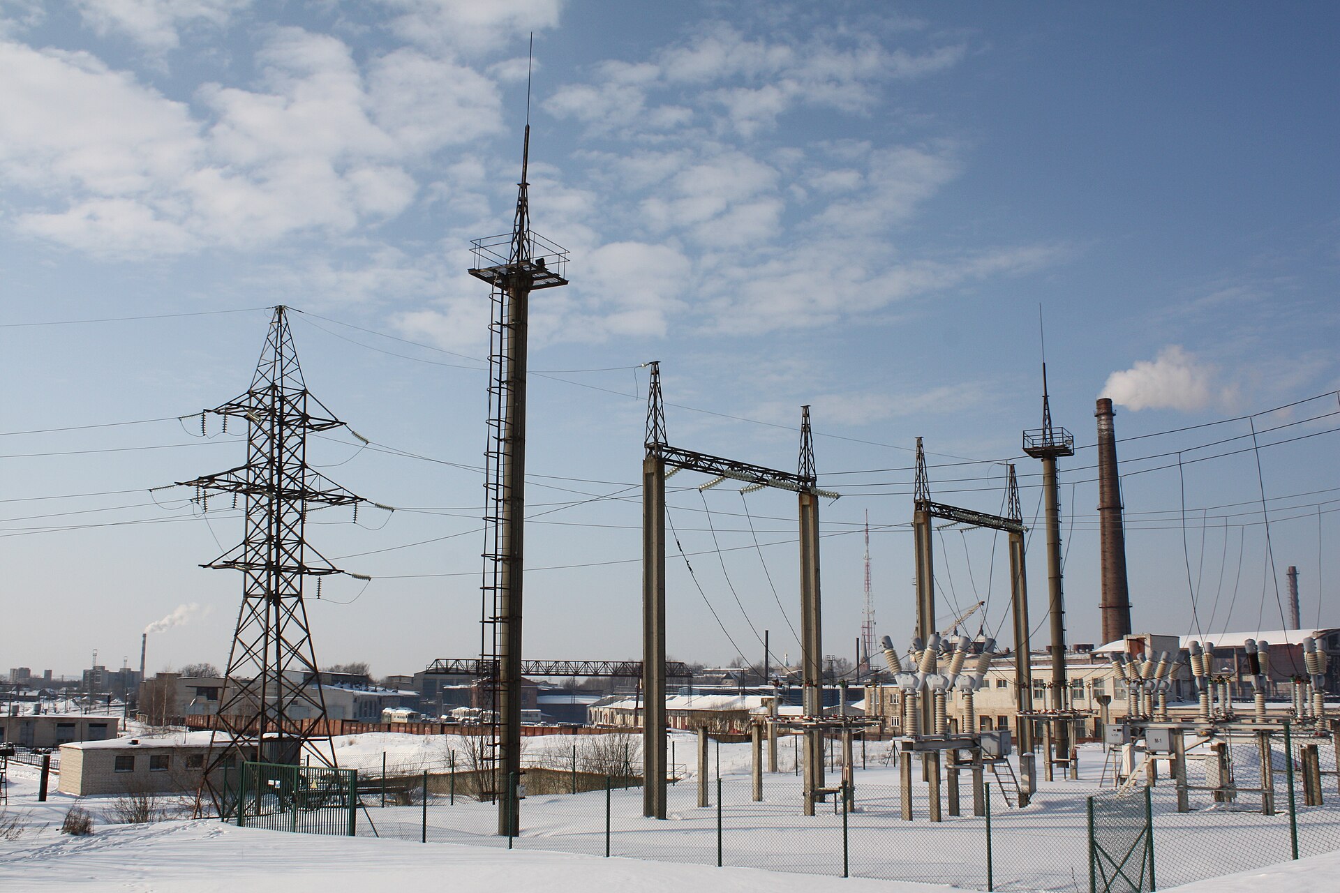 Stacja elektroenergetyczna zimą, słupy i izolatory na tle nieba
